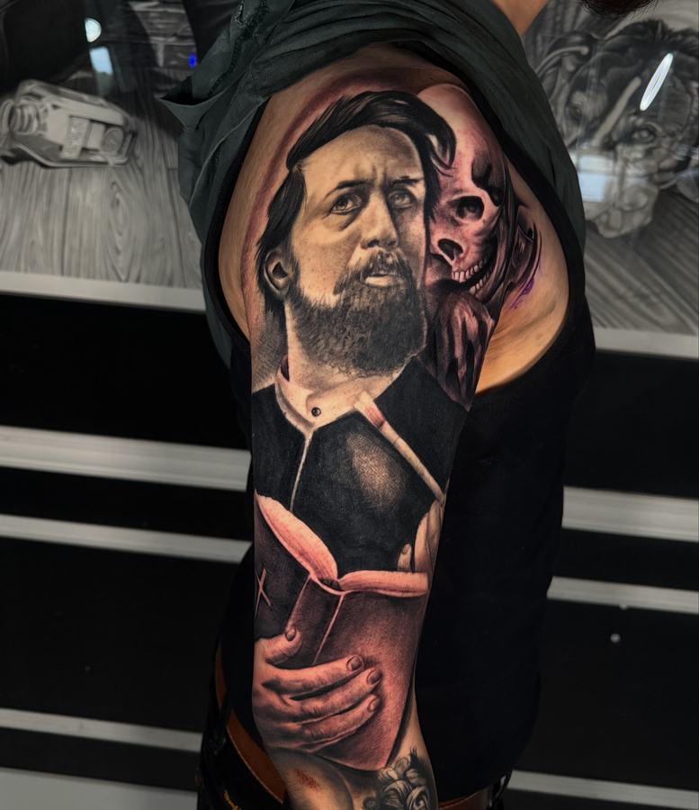 Black and grey realism portrait of a bearded man beside a skull, tattooed on an upper arm sleeve