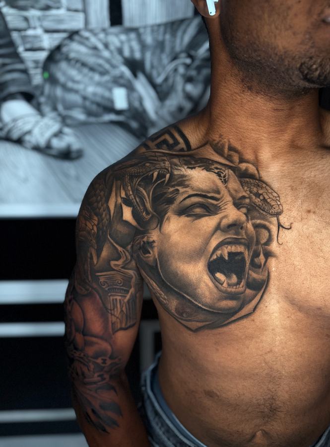 Medusa with snakes in her hair, black and grey realism tattoo across a chest