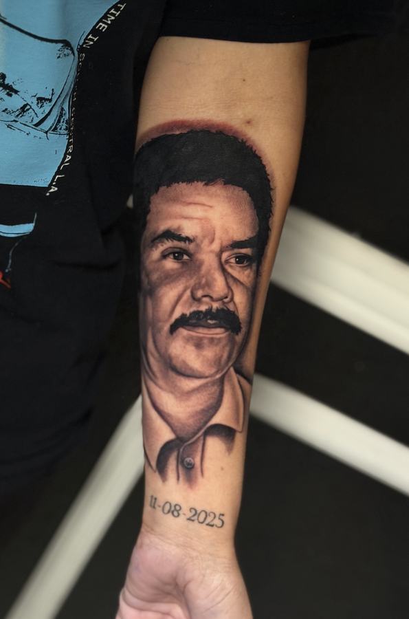 Close view of a black and grey realism memorial portrait tattoo on a forearm