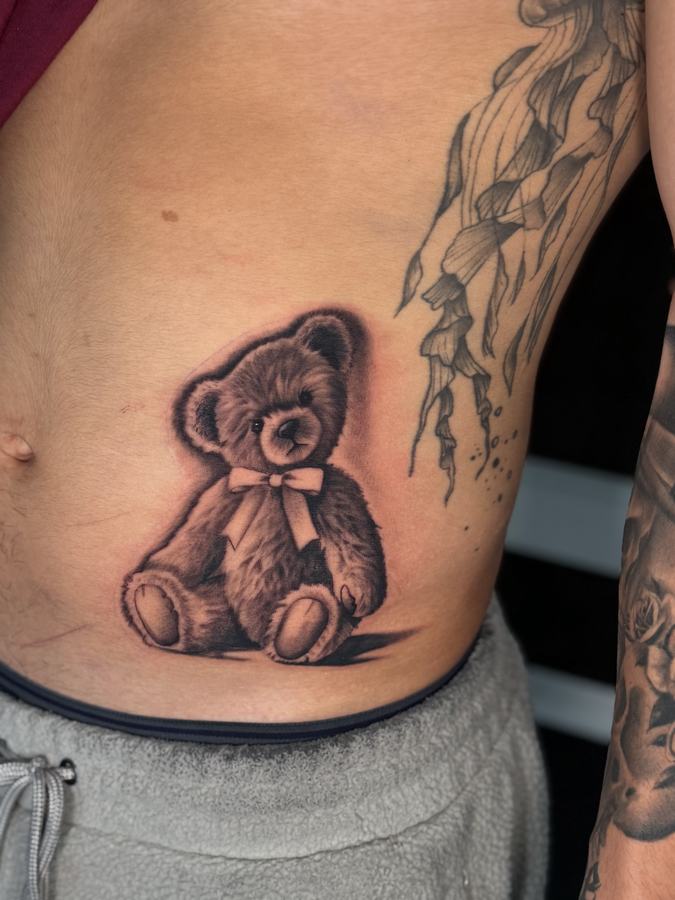 Teddy bear rendered in black and grey realism on the ribs