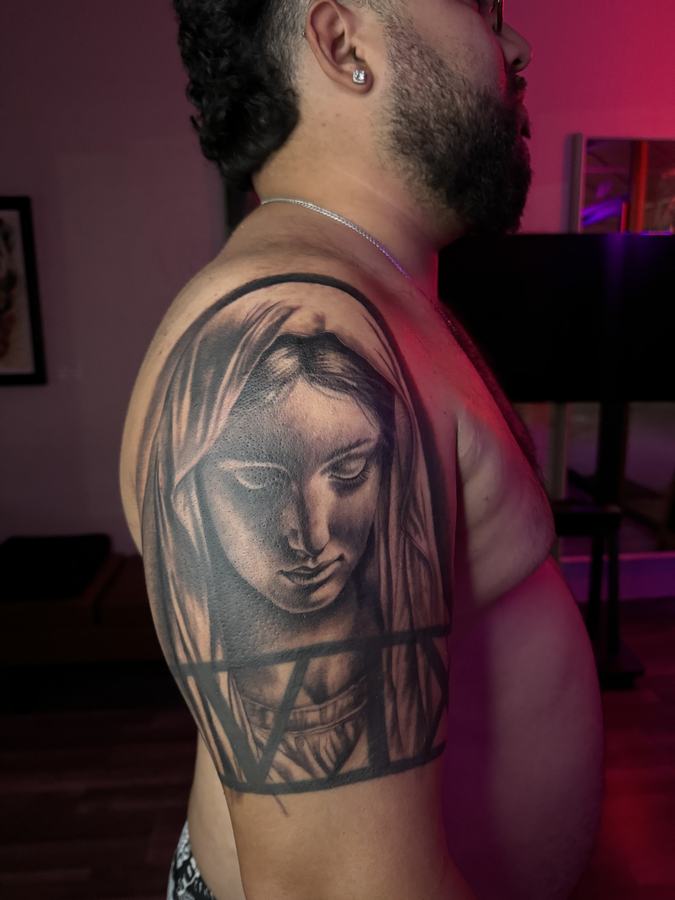 Virgin Mary portrait in black and grey realism tattooed on a shoulder